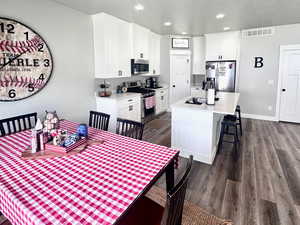 Dining room with dark wood-type flooring, a textured ceiling, and recessed lighting