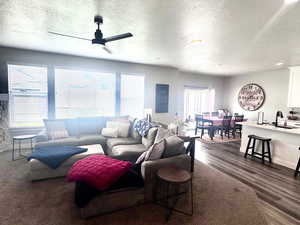 Living area with a textured ceiling, dark wood-style floors, and ceiling fan
