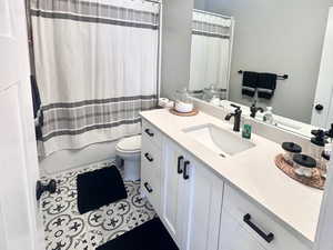 Bathroom with vanity, shower / bath combo with shower curtain, a textured ceiling, and dark tile patterned flooring