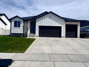 View of front of home with board and batten siding, an attached garage, a front yard, and driveway