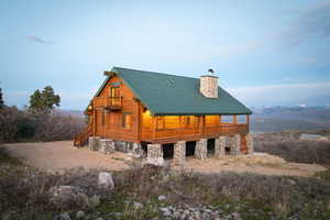 Back of house with a chimney, a metal roof, covered porch, and log exterior