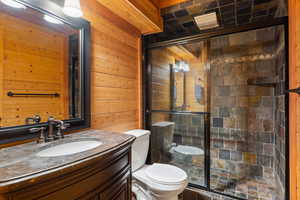Bathroom with wooden walls, vanity, and a stall shower