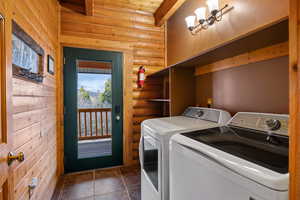 Laundry room with log walls, separate washer and dryer, and dark tile patterned flooring