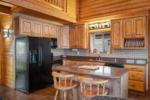 Kitchen with black appliances, a kitchen breakfast bar, a center island, and dark stone countertops