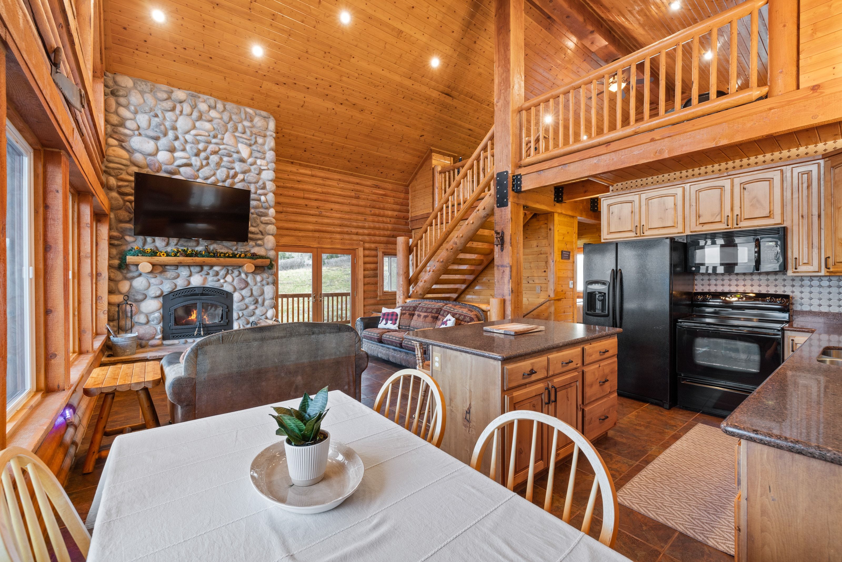 Dining space featuring rustic walls, a vaulted wooden ceiling, a stone fireplace, and recessed lighting