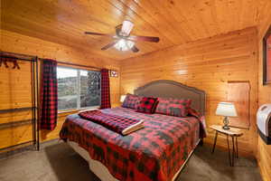 Bedroom with wooden walls, carpet floors, ceiling fan, and wood ceiling