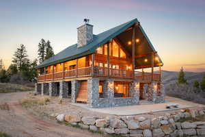 Back of property featuring stone siding, a metal roof, a chimney, and a porch