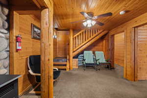 Bedroom featuring wooden walls, carpet flooring, wooden ceiling, and a ceiling fan