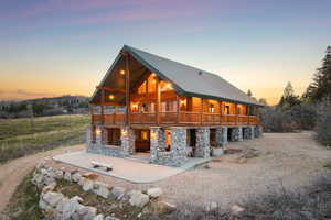 Back of property at dusk with a metal roof, stone siding, and a large porch
