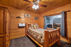 Bedroom featuring wooden walls, ceiling fan, carpet floors, heating unit, and wood ceiling