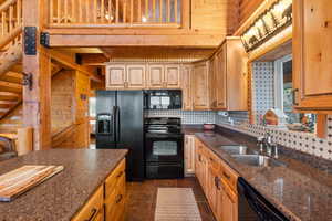 Kitchen featuring black appliances, dark stone counters, wooden ceiling, decorative backsplash, and wood walls