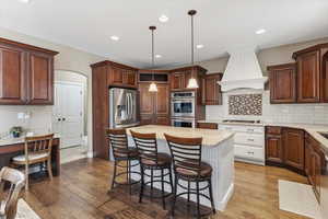 Large island with seating, double ovens, stainless steel appliances, and two-tone skyline cabinetry create a kitchen designed for gathering, with access to a huge hidden pantry.