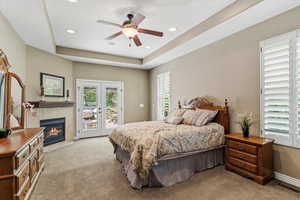 Primary suite on the first level featuring tray ceilings, a gas fireplace, private access to the back patio, and abundant natural light.