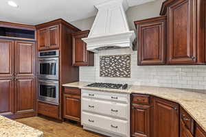 Double ovens, subway tile backsplash, upgraded granite countertops, and two-tone skyline cabinetry highlight this kitchen with stainless steel appliances and thoughtful design.
