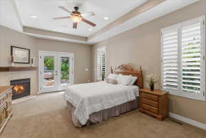 Primary suite on the first level featuring tray ceilings, a gas fireplace, private access to the back patio, and abundant natural light.