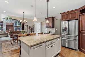 Upgraded granite countertops, stainless steel appliances, and a large island create a functional kitchen space that opens to gathering areas and a gas fireplace.