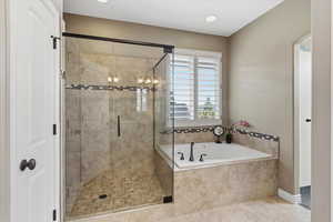 Primary bathroom featuring a large glass shower, separate jetted tub, and double vanity with upgraded finishes.