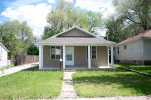 Bungalow-style home with a porch, roof with shingles, and a front yard