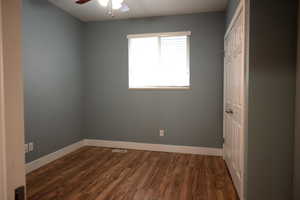Unfurnished bedroom with dark wood-style floors, a ceiling fan, and a closet
