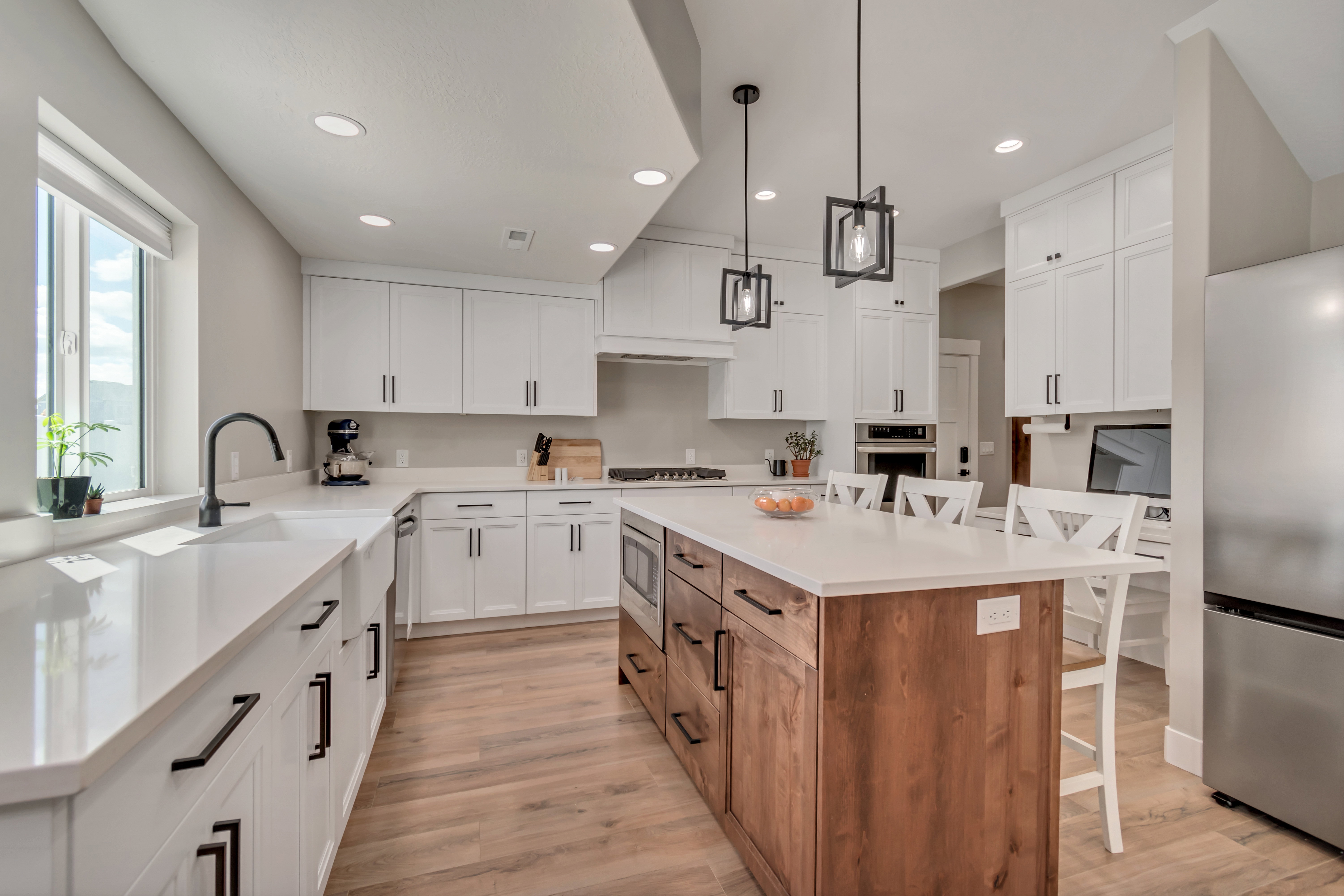 Kitchen with a breakfast bar area, two tone cabinetry, stainless steel appliances, a kitchen island, and light wood-style flooring