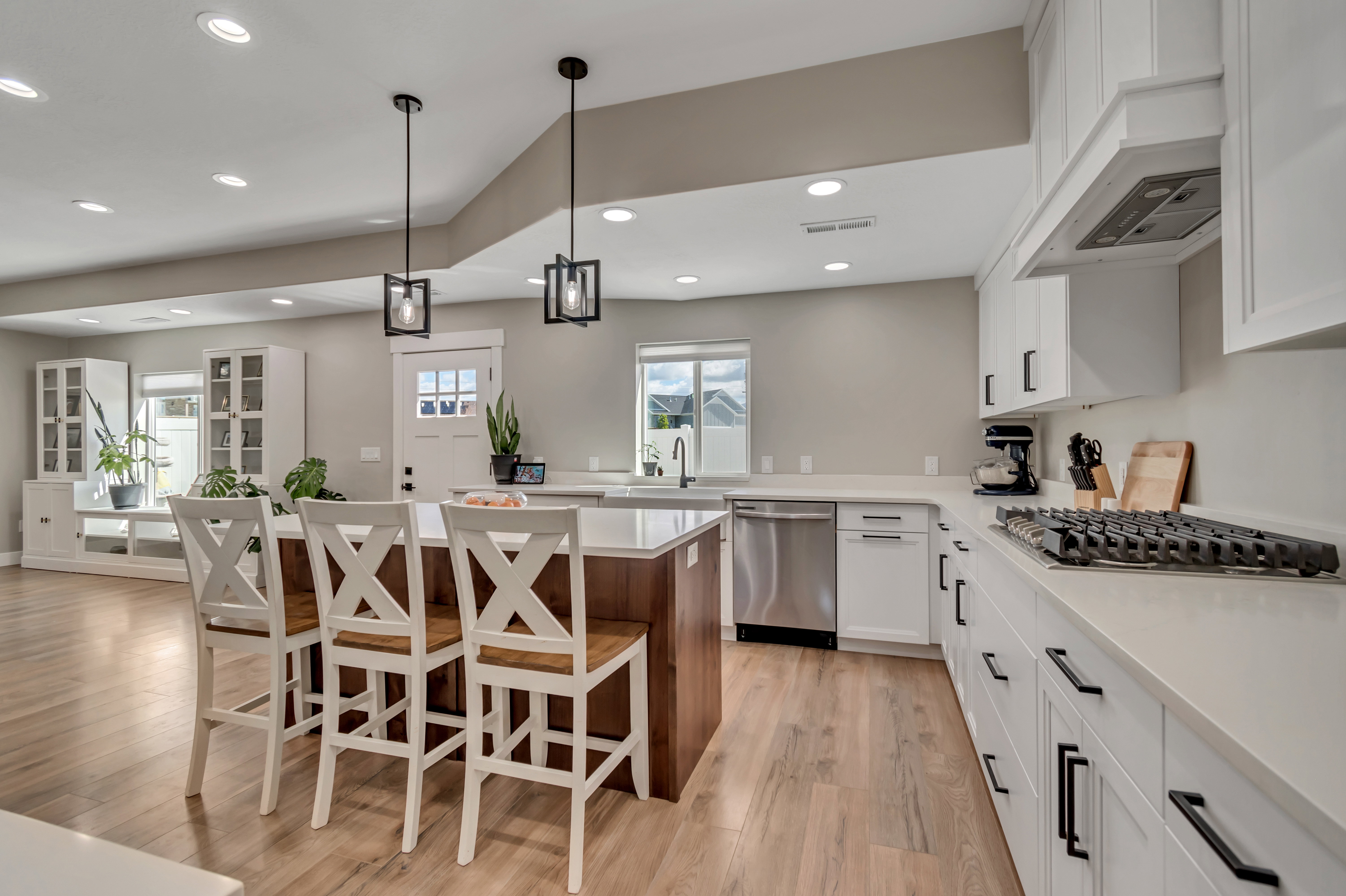 Kitchen with light wood-style floors, two tone color scheme, a kitchen island, pendant lighting, and stainless steel appliances