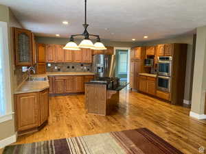 Kitchen with wood finish cabinets, stainless steel appliances, a center island, decorative backsplash, and glass fronted cabinets