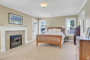 Bedroom featuring light carpet, a tile fireplace, crown molding, and access to exterior