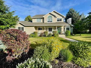 View of front of home with a porch, a front yard, a chimney, and roof with shingles