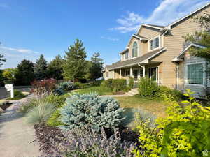 View of grassy yard featuring covered porch