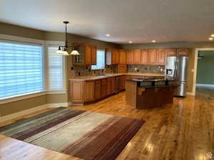 Kitchen with wood finish cabinets, stainless steel appliances, a center island, light wood finished floors, and a kitchen bar