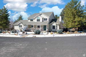 View of front of property with covered porch, a shingled roof, and a chimney