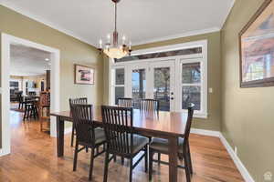 Dining room featuring hardwood / wood-style floors, hanging lights, crown molding, and french doors