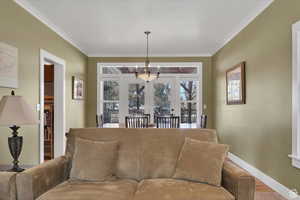 Living area with suspended lighting, crown molding, and wood finished floors