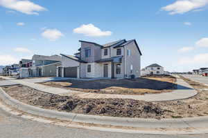View of front of home featuring a residential view, driveway, stone siding, and an attached garage