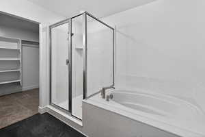 Bathroom with a spacious closet, a marble finish shower, and a garden tub
