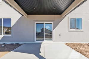 Doorway to property featuring stucco siding and a patio