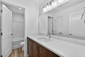 Full bathroom featuring vanity, light wood-style flooring, and washtub / shower combination