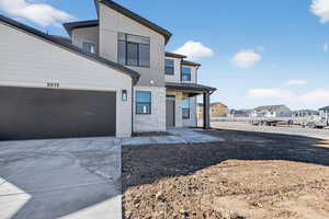 Modern home featuring a porch, a standing seam roof, a residential view, stone siding, and concrete driveway