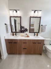 Dual wood-finish vanity with integrated sinks, quartz-finish countertop, dark-framed mirrors, and contemporary light fixtures
