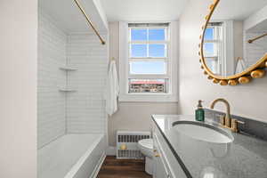 Bathroom with vanity, radiator, dark wood-style flooring, and bathing tub / shower combination