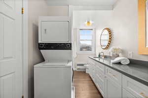 Laundry area featuring dark wood-style floors and stacked washer / dryer