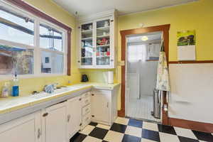 Kitchen with white cabinetry, light floors, tile counters, and glass fronted cabinets