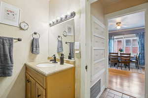 Bathroom featuring vanity, a ceiling fan, a textured wall, and light tile patterned floors