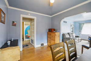 Dining area featuring crown molding, ceiling fan, wood finished floors, and arched walkways