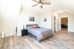 Bedroom featuring vaulted ceiling, light wood-style flooring, and a ceiling fan