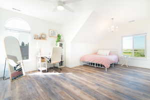 Bedroom featuring a desk, wood finished floors, suspended lighting, a ceiling fan, and vaulted ceiling