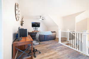 Home office featuring light wood-style floors, ceiling fan, and vaulted ceiling