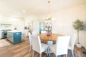 Dining area with a decorative wall, dark wood-style floors, and hanging lights