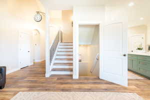 Stairs featuring wood finished floors, arched walkways, recessed lighting, and a high ceiling