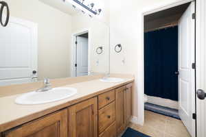 Bathroom featuring double vanity, light tile patterned floors, and shower / bathtub combination with curtain
